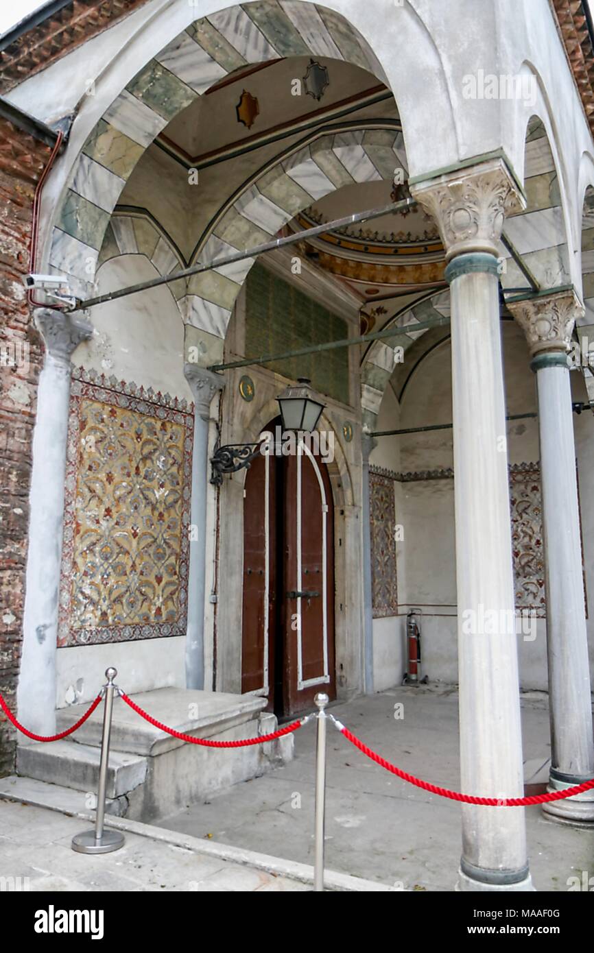 Außenansicht, von einem niedrigen Winkel, in dem die ottomanischen Stil, gewölbt und gewölbte Säulenaufgang, mit korinthischen Säulen, bunte Kacheln, Sitzbank, und großen gewölbten Türen in die Aya Irini (Hagia Irene), einem ehemaligen griechischen Orthodoxen Kirche führenden, jetzt als Museum und Konzertsaal, im äußeren Hof des Topkapi-Palastes in Istanbul, Türkei, 16. November 2017 verwendet. () Stockfoto