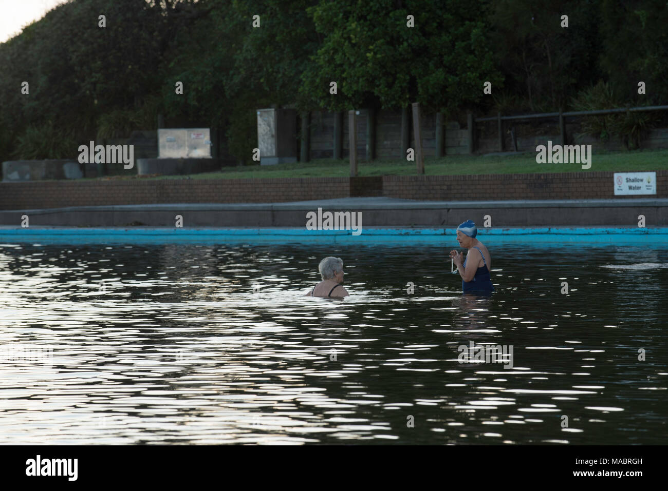 Zwei Frauen in einem großen Ocean Pool Chatten nur auf Dawn bei Forster in der Mitte der Nordküste von New South Wales, Australien Stockfoto