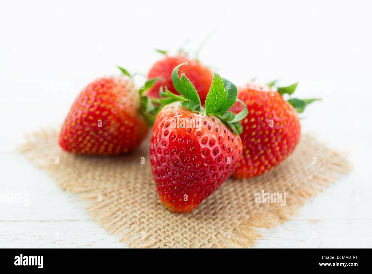 Frische Erdbeeren auf sackleinen und weißem Holz Hintergrund mit selektiven Fokus Stockfoto