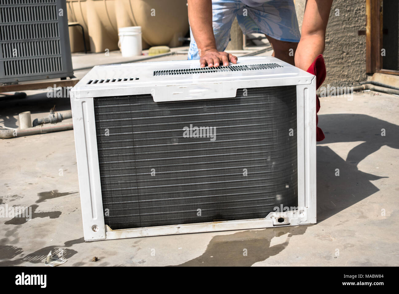 Einen professionellen Elektriker ist die Reinigung der Fenster Klimaanlage auf dem Dach eines Hauses mit einem feuchten Serviette Stockfoto