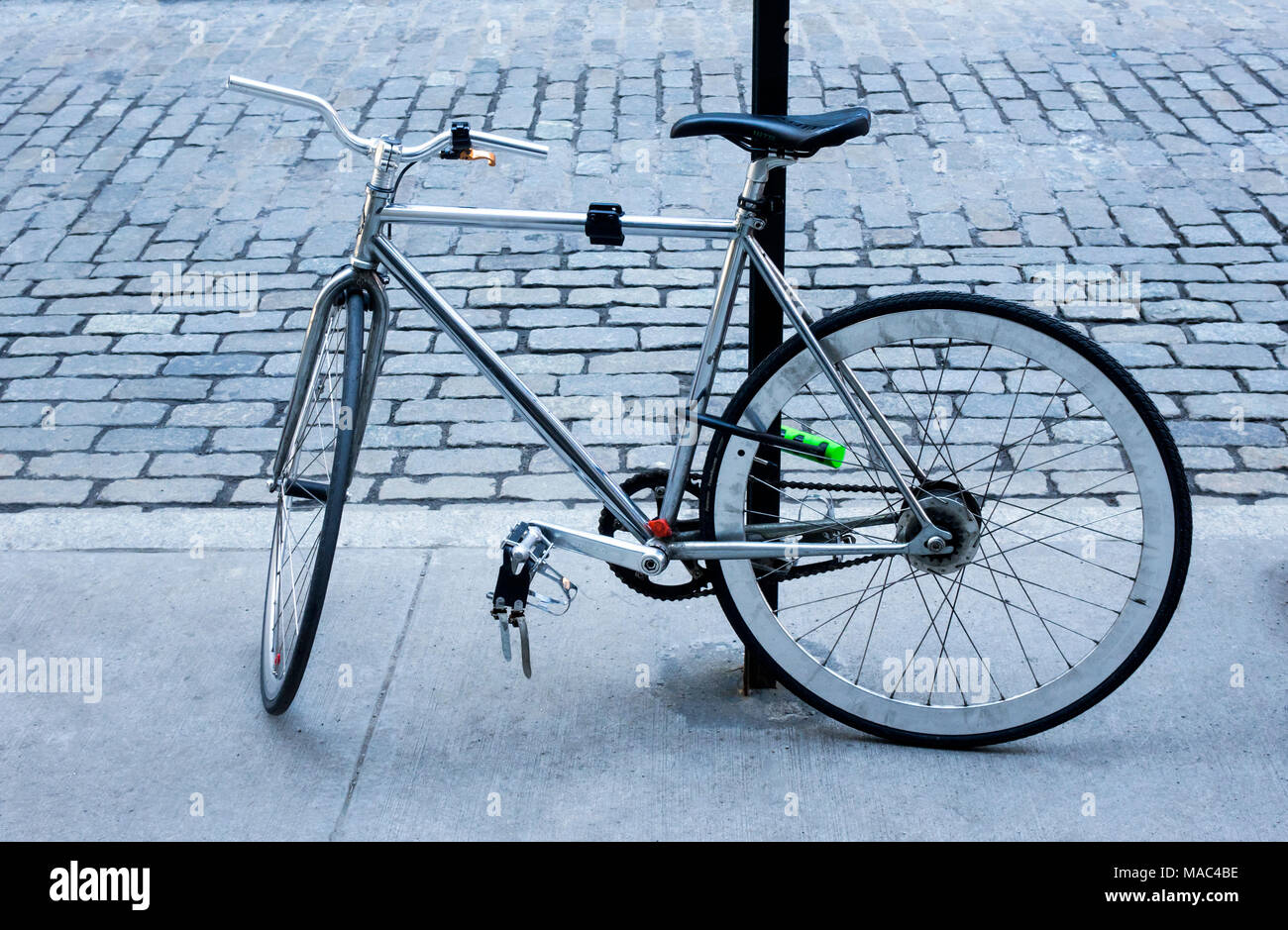 Der Mann mit dem Fahrrad auf einen Post auf einer gepflasterten Straße in New York City gesichert Stockfoto