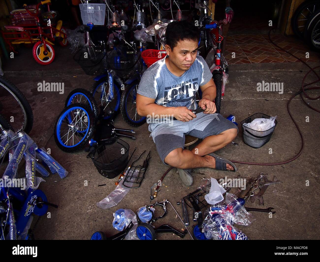 ANTIPOLO CITY, Philippinen - 28. MÄRZ 2018: ein Fahrrad Shop Mitarbeiter behebt ein Fahrrad für einen Kunden Stockfoto