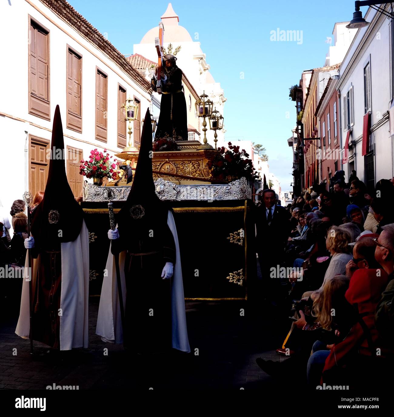 Büßer Spaziergang feierlich vor reich verzierten Float mit Christus mit Kreuz im 'La Magna "Heiligen Woche Prozession an Ostern, La Laguna, Teneriffa, Kanarische Inseln Stockfoto