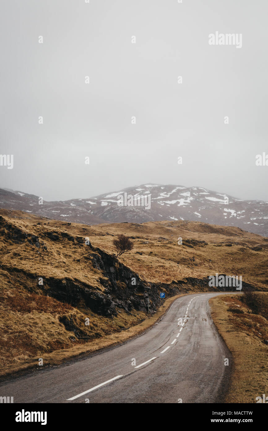 Eine Straße, die durch die schottischen Highlands nahe Lochinver an einem nebligen Frühlingstag. Stockfoto