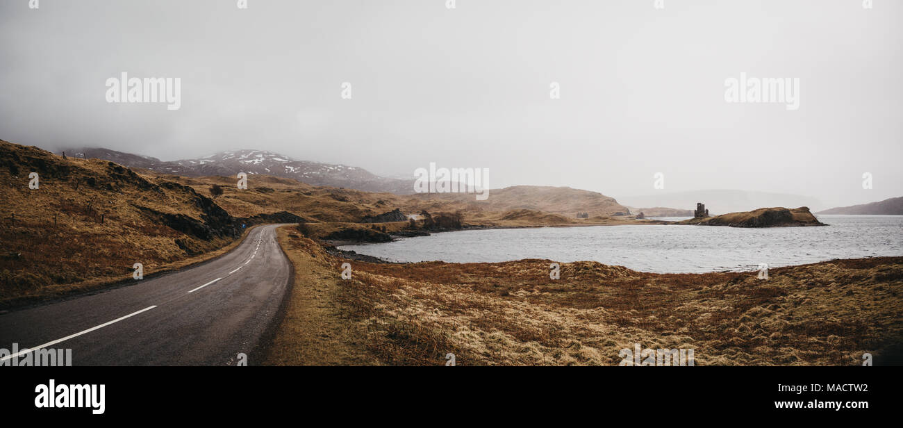 Eine Straße, die durch die schottischen Highlands nahe Lochinver an einem nebligen Frühlingstag. Stockfoto