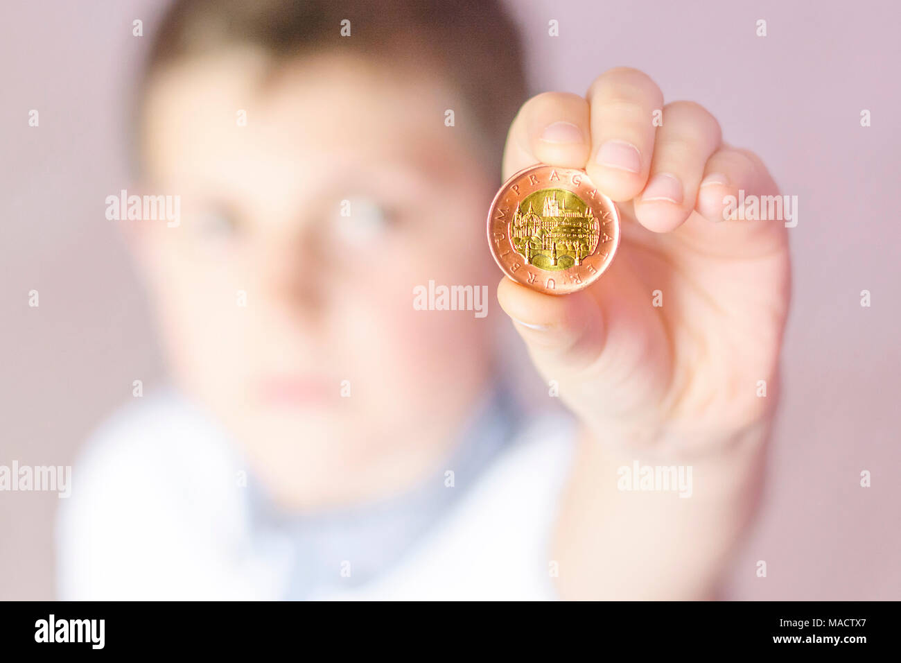 Little boy Holding eine Münze in der Hand. Junge, zu denken, was mit Einsparungen zu tun. Kind Geld sparen. Geld aus der Tschechischen Republik. Stockfoto