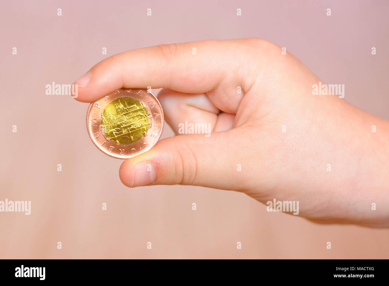 Metall Münze zwischen den Zehen der kleinen Jungen. Eine Hand mit einem tschechischen Münze. Stockfoto