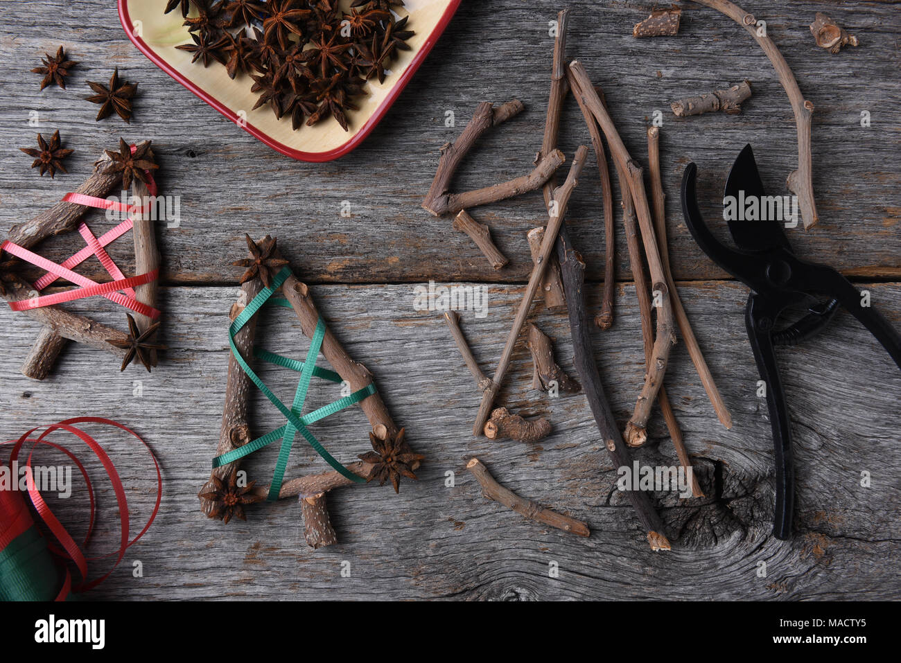 Ansicht von oben auf die Geräte und Materialien für die rustikale Weihnachtsschmuck, einschließlich Zweige, Sternanis, Scheren, und Farbband. Stockfoto