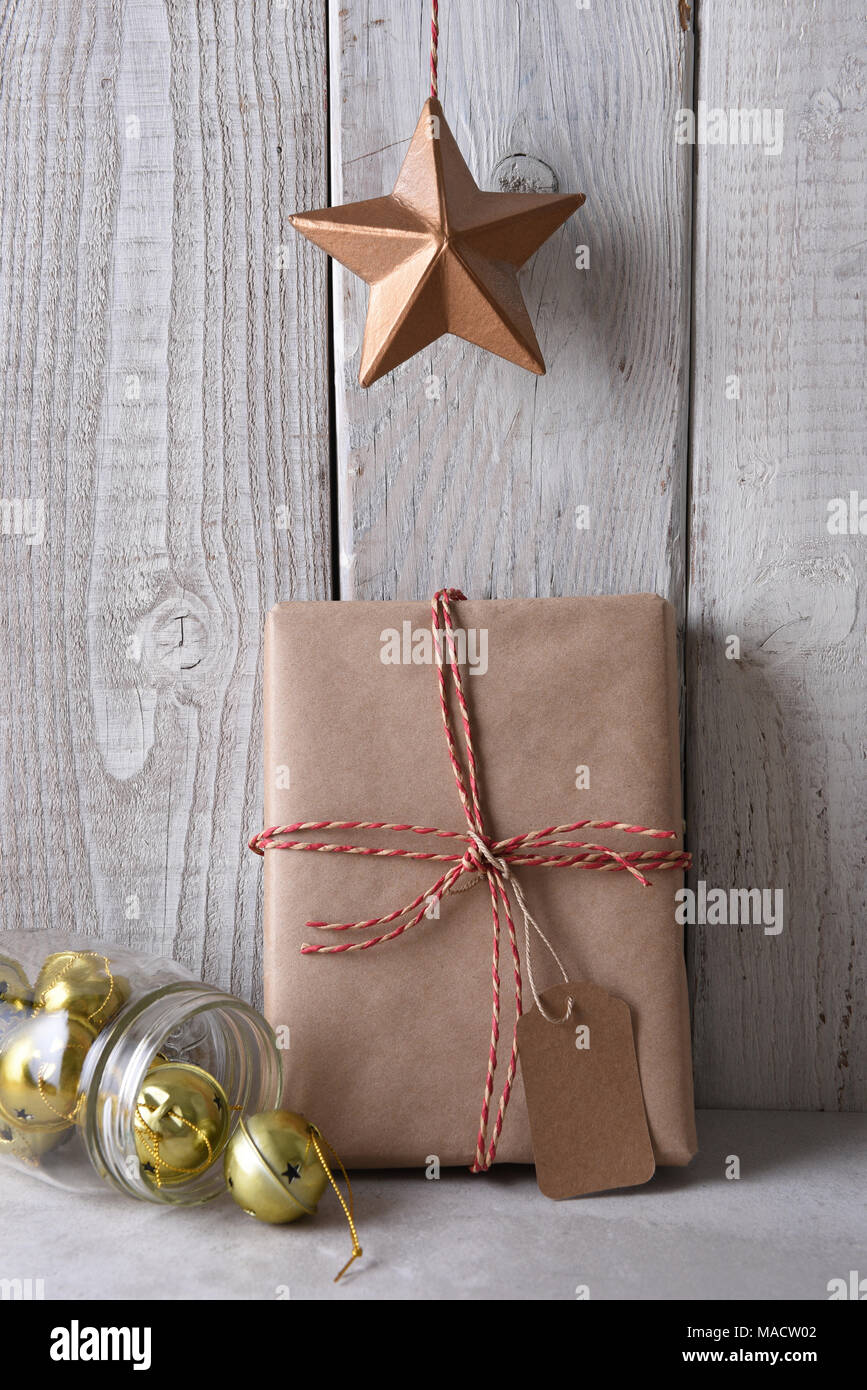 Star hängt über einem einfachen braunen Papier eingewickelt Weihnachtsgeschenk. Die Gegenwart ist leanng auf einem urigen getünchte Wand. Stockfoto