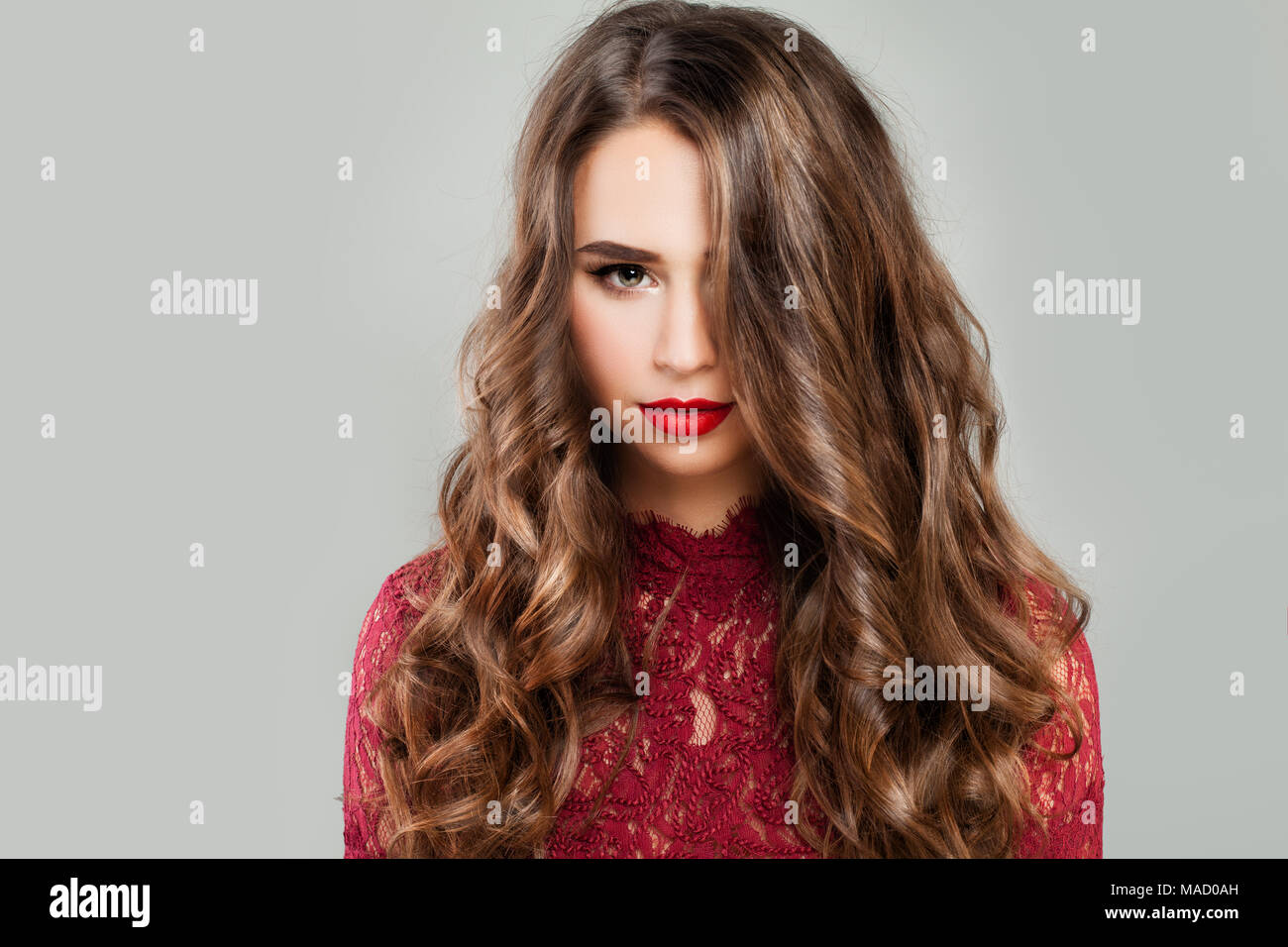 Süße Frau mit langen Welligen Frisur und Make-up. Schöne junge Modell mit roten Lippen Make up auf Banner Hintergrund Stockfoto