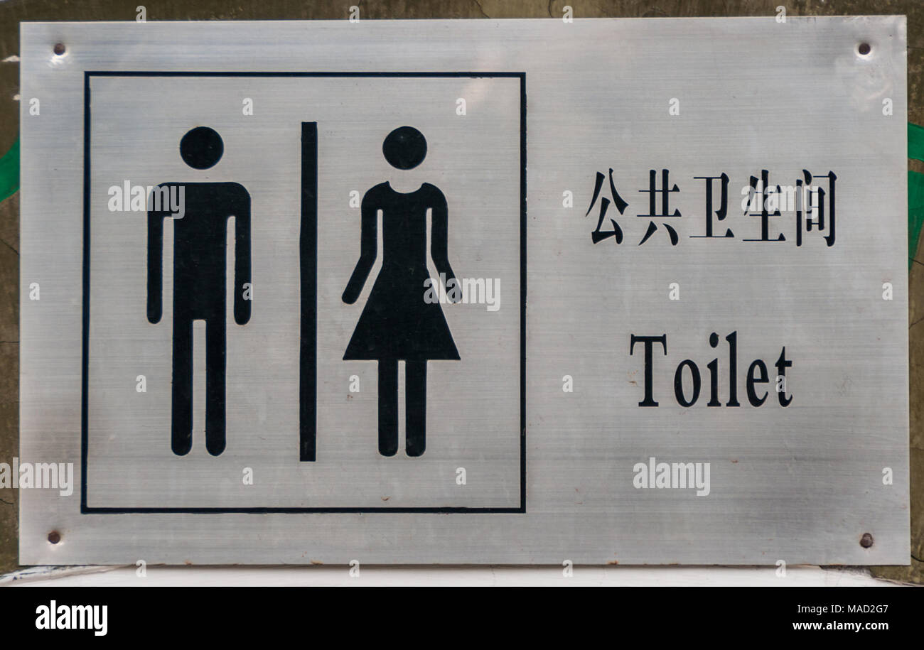 Peking, China - 26. April 2010: Nahaufnahme von grau Metall öffentliche Toilette Schild an Wand an Tuanjiehu Park zeigt Mandarin und Englisch Text plus Männlichen und Fema Stockfoto