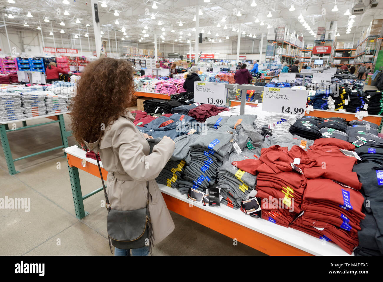 Frau Kommissionierung ein T-Shirt auf der Costco Wholesale Mitgliedschaft Lagerverkauf Herrenbekleidung Abschnitt. British Columbia, Kanada 2017. Stockfoto