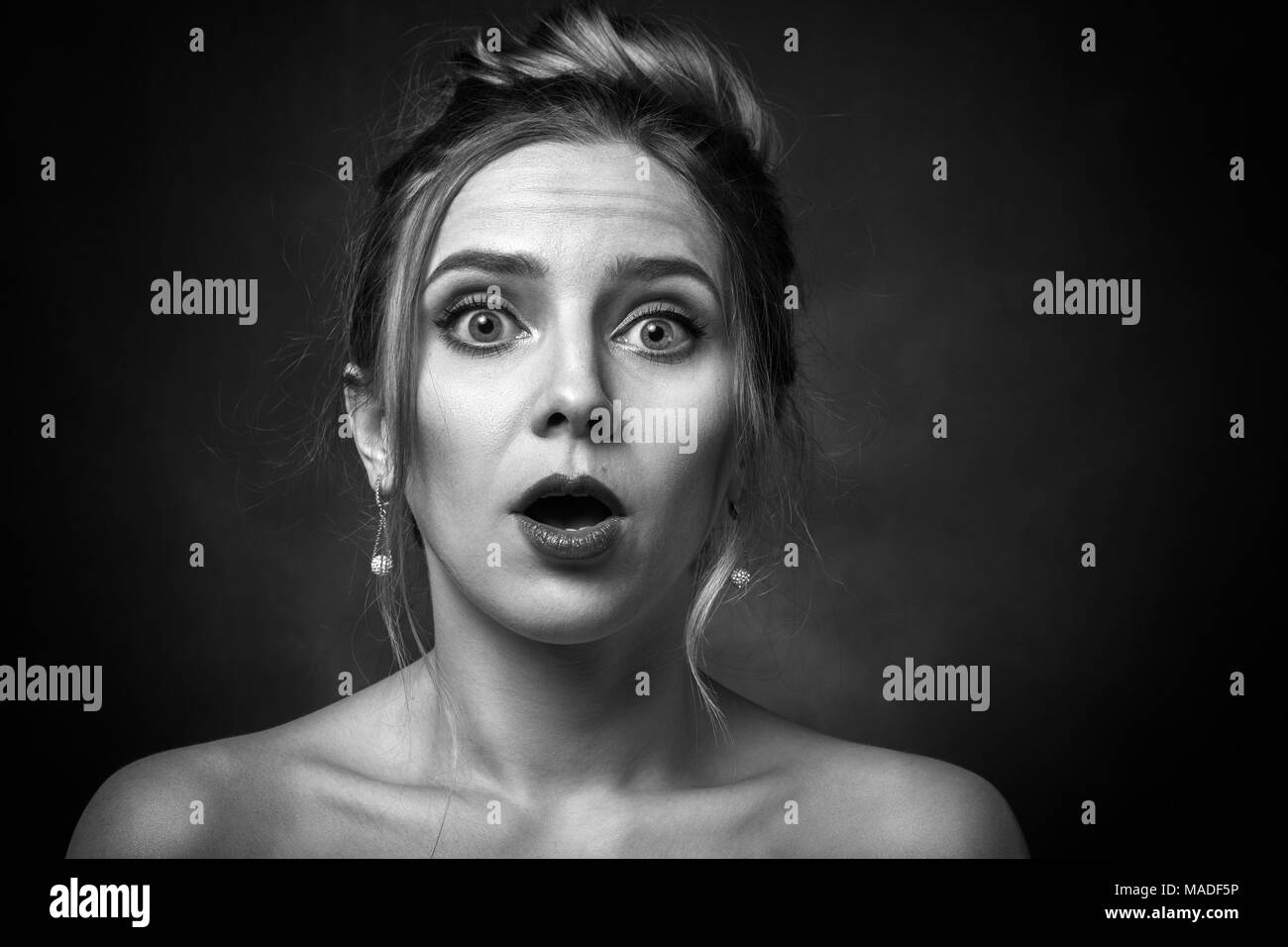Schockiert Frau mit offenen Mund auf schwarzem Hintergrund an Kamera suchen, Schwarzweiß Stockfoto