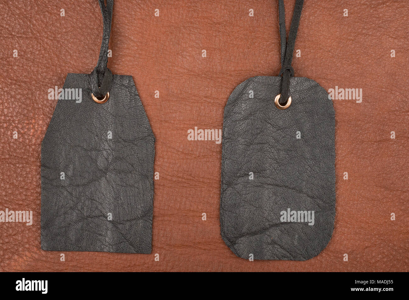 Zwei leere schwarze Leder tag Label auf braunem Leder. Ansicht von oben Stockfoto