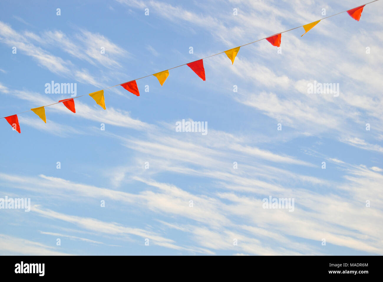 Mehrfarbige dreieckige Flaggen, isoliert gegen einen Himmel mit Wolken Stockfoto