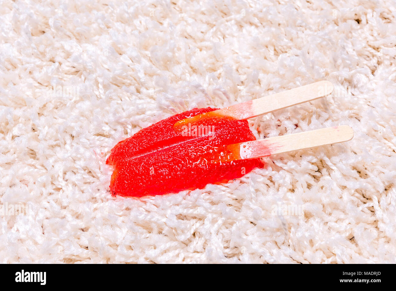 Einem Time Lapse-Videorecorder eines schmelzenden Popsicle auf weißen Teppich zeigt die eisigen behandeln in einem klebrigen Saft schmelzen und rechts in den Teppich zu absorbieren. Stockfoto