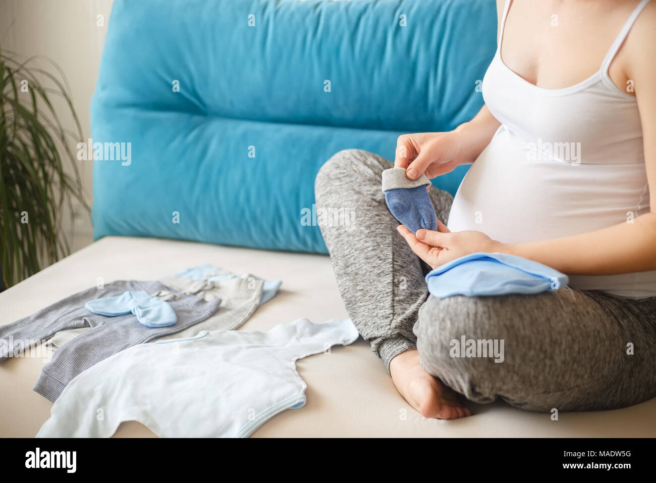 Nahaufnahme der schwangeren Frau Vorbereitung Baby Kleidung. Die werdende Mutter mit Kleidung für das Neugeborene. Schwangerschaft, Menschen, Erwartung von baby Konzept Stockfoto