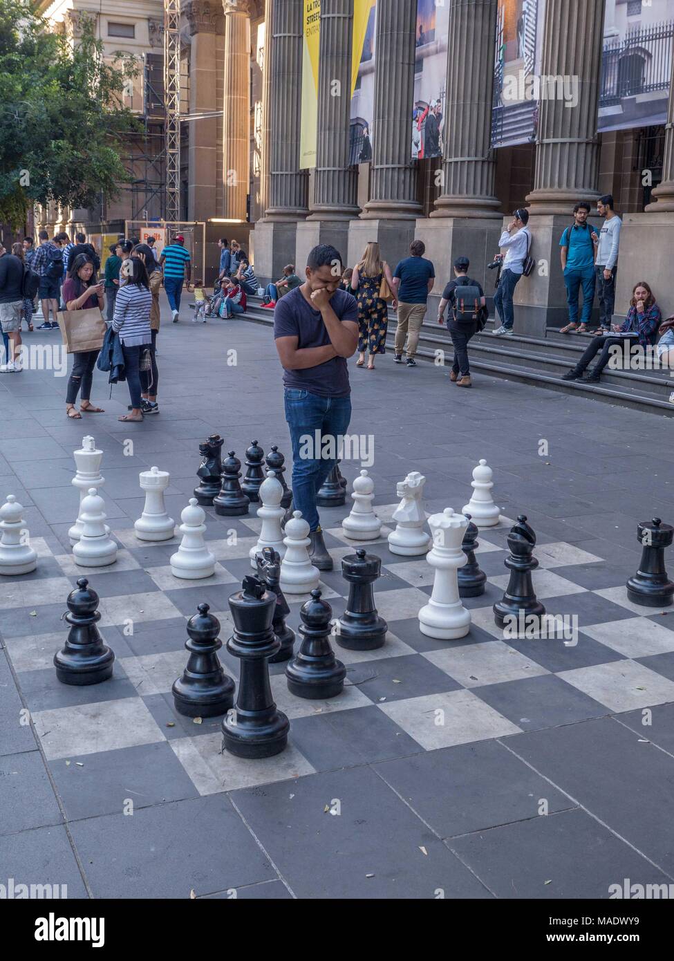 Menschen Schach spielen auf grossen Pflaster Schachbrett vor der Staatsbibliothek von Victoria mit Bibliothek spalten und Banner im Hintergrund. Stockfoto