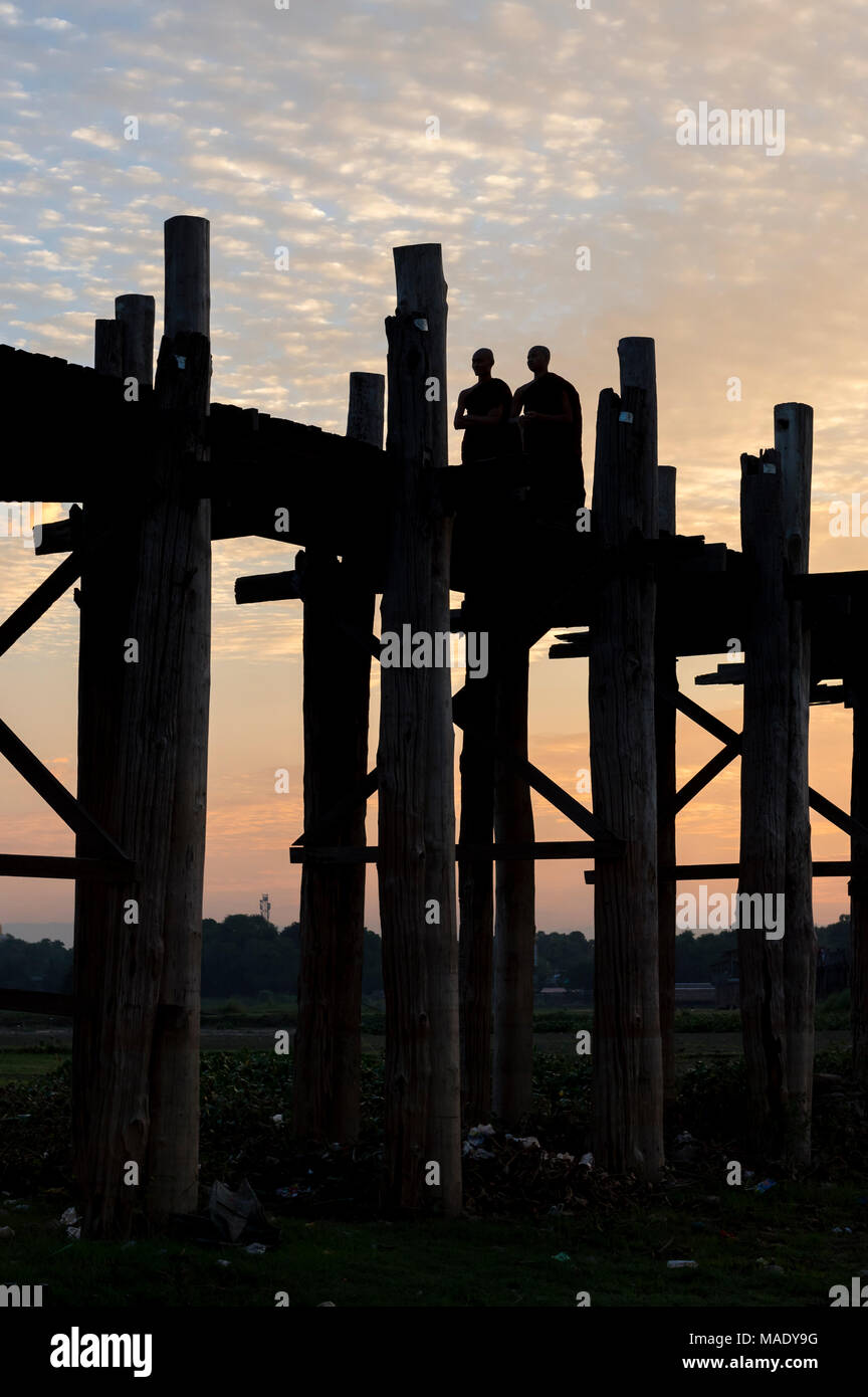 Buddhistische Mönche gehen Sie auf die U-Bein Brücke bei Sonnenaufgang, Amarapura, Mandalay, Burma (Myanmar) Stockfoto