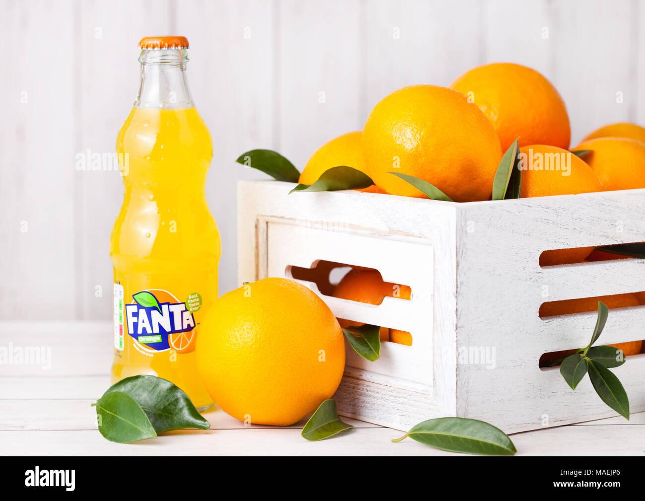 LONDON, UK, 31. MÄRZ 2018: Glas Flasche Fanta Orange Soft drink auf weißem Hintergrund mit Holz, der Rohstoff Orangen Stockfoto