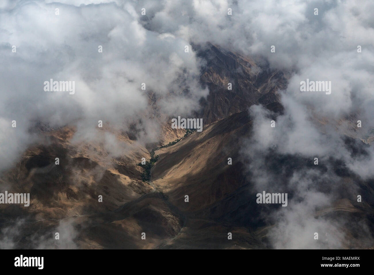 Berg Tal zwischen den Wolken, ein Foto mit einer großen Höhe: Die braunen noch Hänge des Berges, unten die Schlucht erstreckt sich ein Streifen von Greene Stockfoto