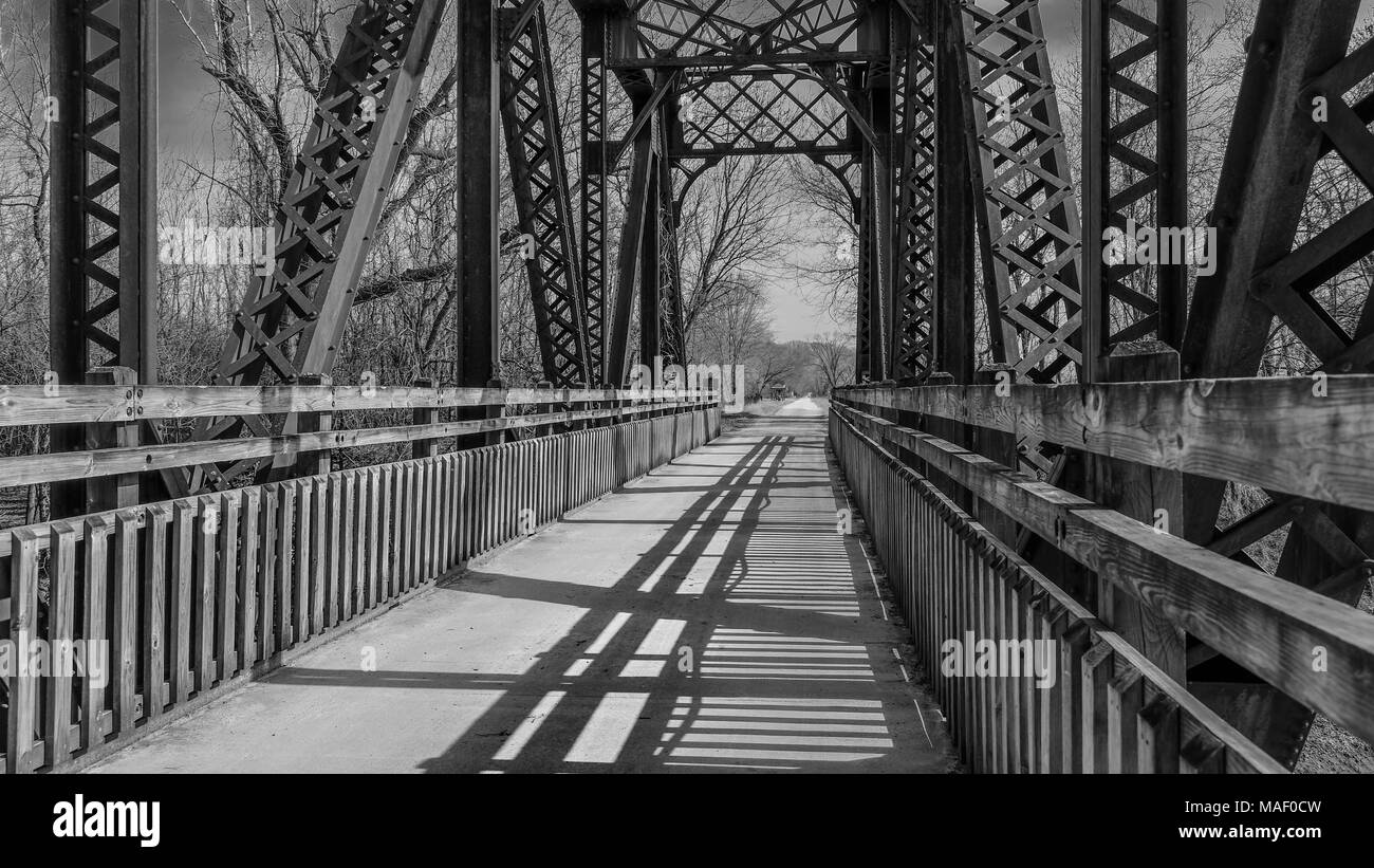 Blick auf eine alte Eisenbahnbrücke umgewandelt in einen Park Trail; Missouri, Mittelwesten; Schwarz und Weiß; lange Schatten Stockfoto