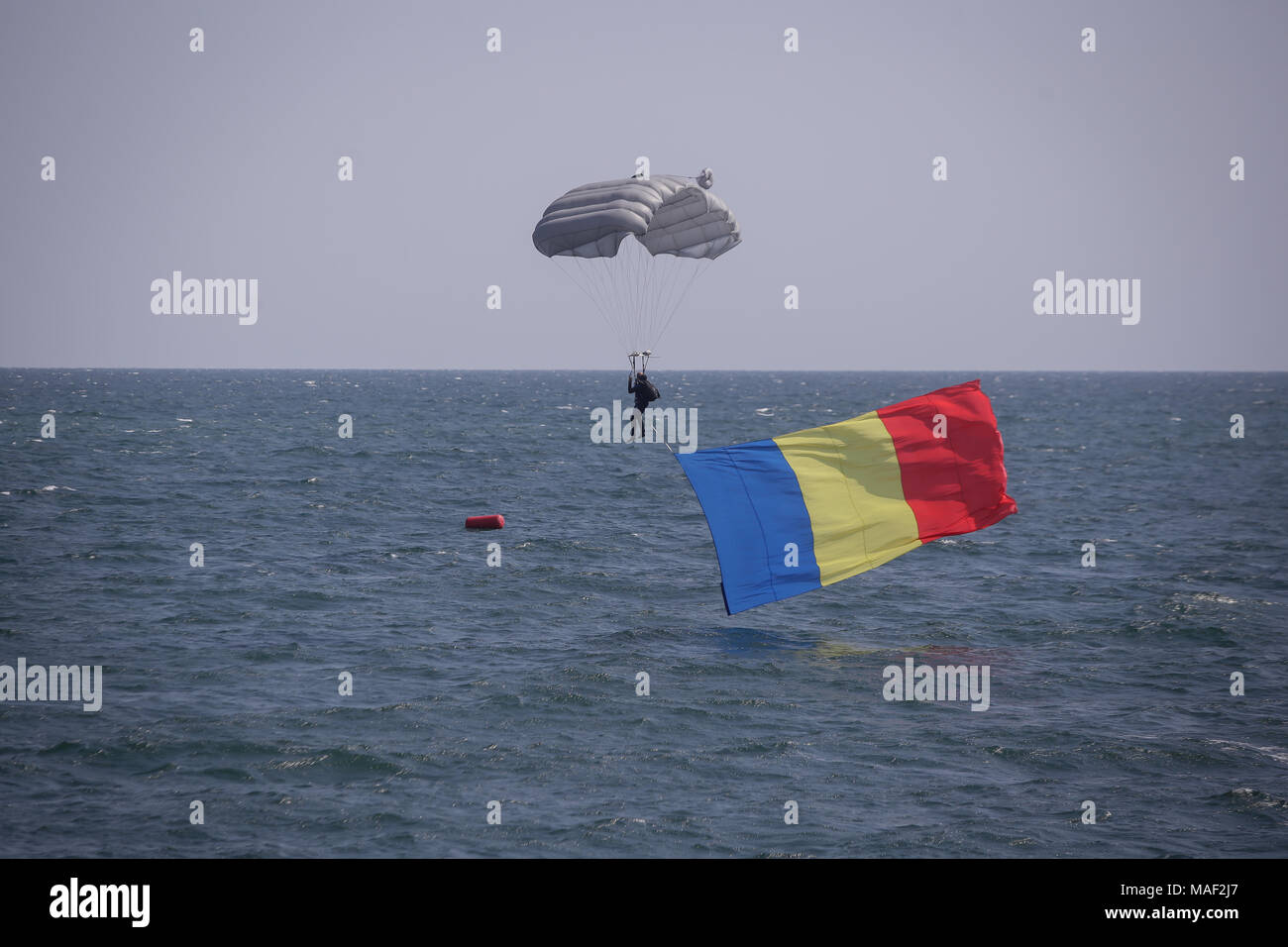 Eine rumänische Marine Fallschirmjäger landen im Wasser mit der rumänischen Flagge, während die rumänische Marine Tag Stockfoto