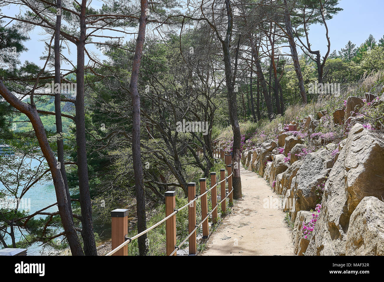 Schmutz weg mit Holzgriffen auf der linken und der felsigen Wänden rechts mit Blick auf einen See abwärts im Sanjeong See von Pocheon, Südkorea. Stockfoto