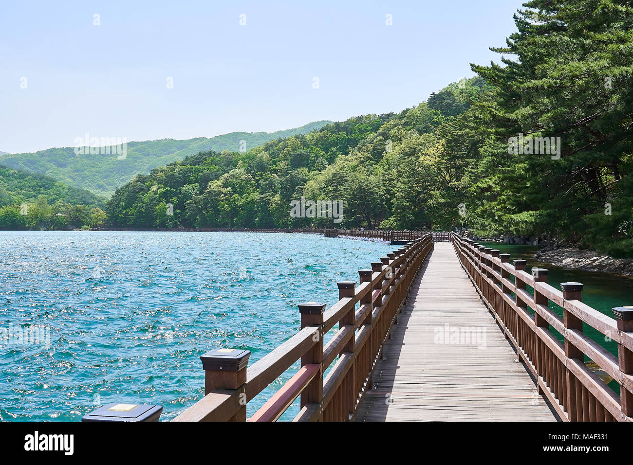 Holz- weg auf einem blauen See mit Blick auf die Bäume und Hügel am Horizont mit blauen Himmel von Sanjeong See in Pocheon, Südkorea. Stockfoto