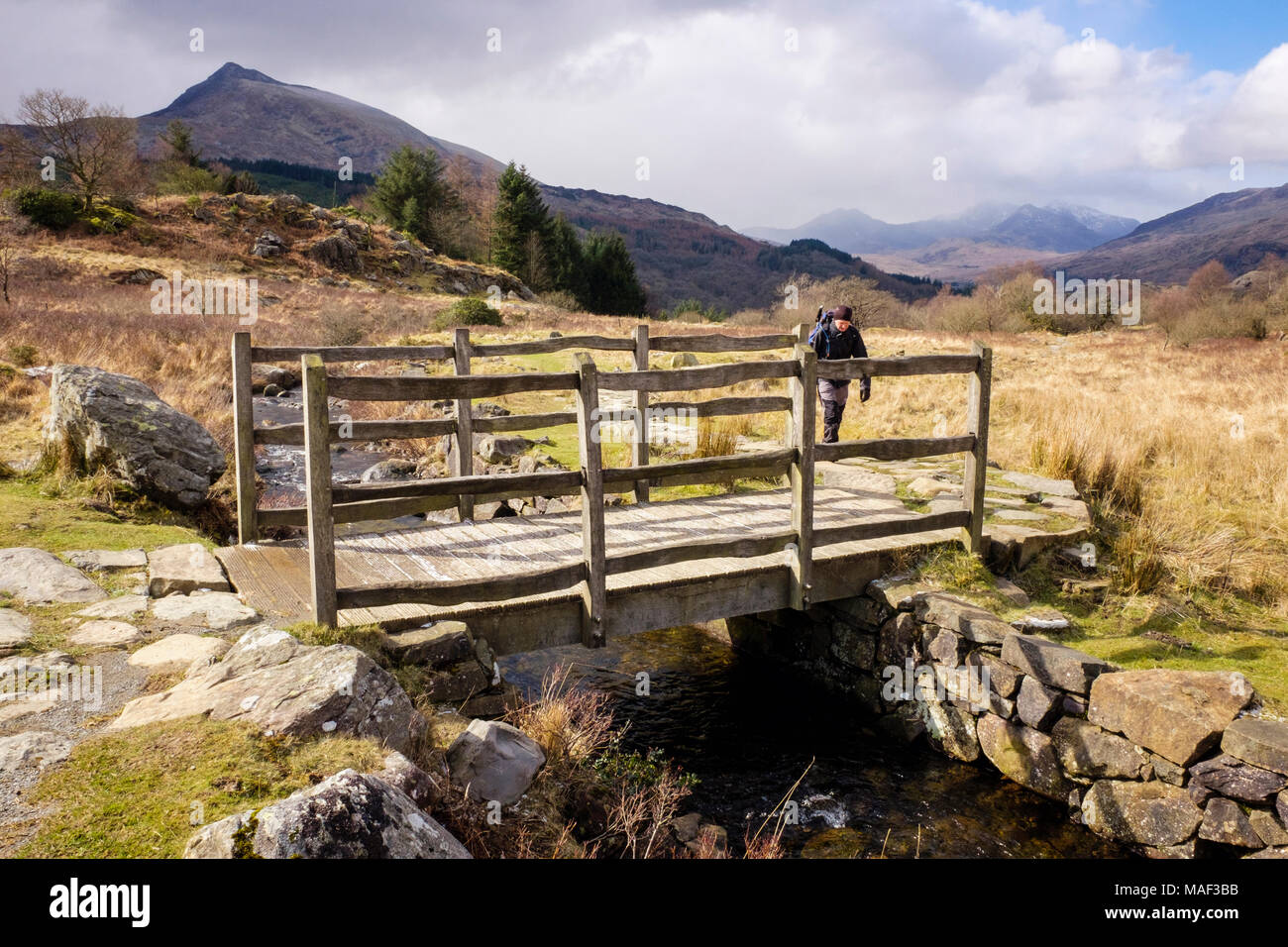 Wanderer auf ein Land zu Fuß nähern Holzsteg Überquerung eines Datenstroms auf einem Wanderweg in Snowdonia National Park. Capel Curig Conwy Wales UK Großbritannien Stockfoto