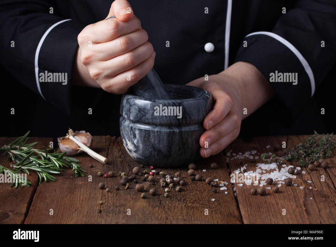 Frau Koch schlagen Gewürze und Kräuter in Mörtel für Essen kochen auf einem  schwarzen Hintergrund Stockfotografie - Alamy