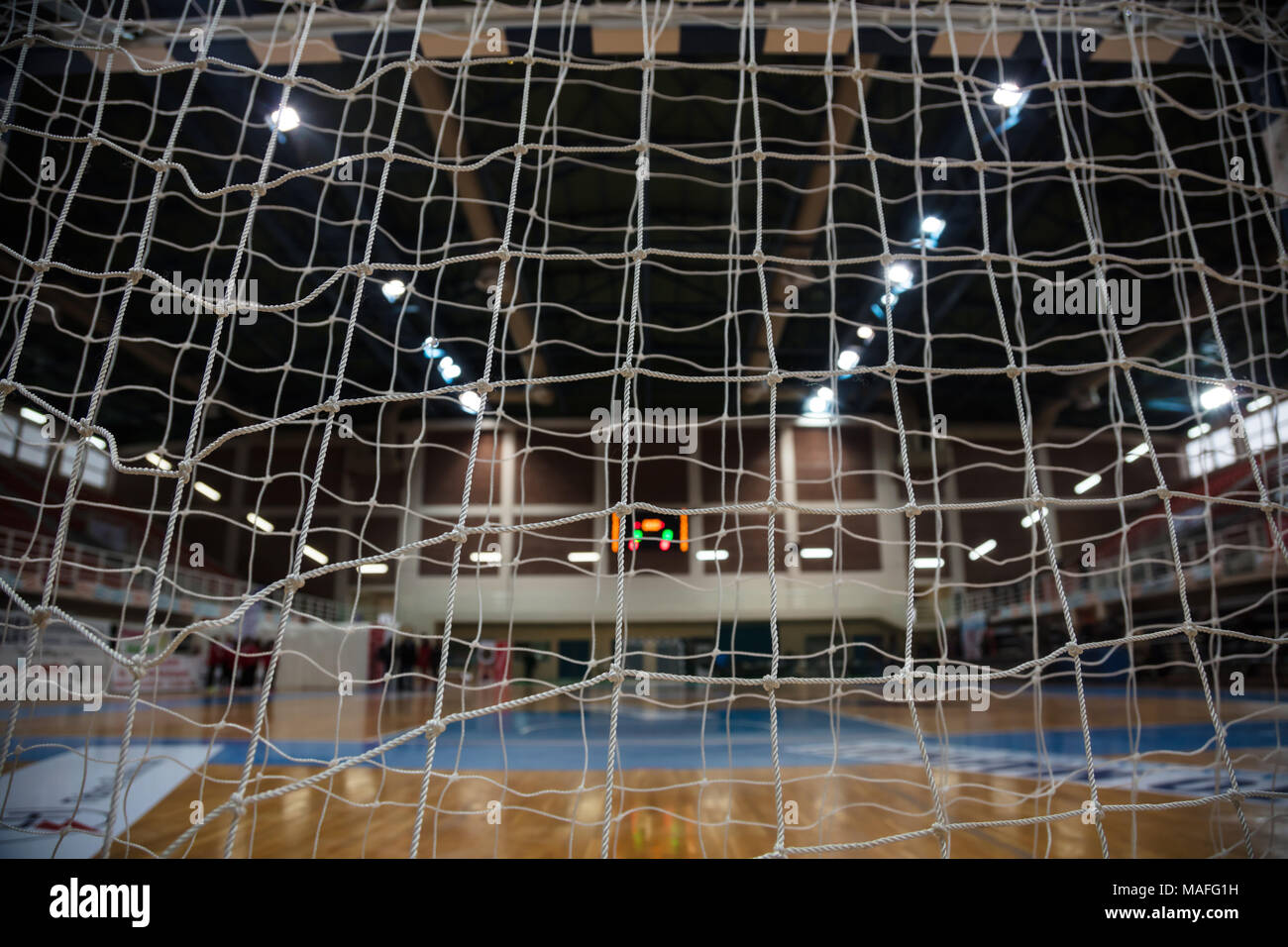 Handball Konzept. Close up Ziel post Netze von hinten anzuzeigen. Verschwommen Hof, Sportler und Elektronische Anzeigetafel Hintergrund. Stockfoto