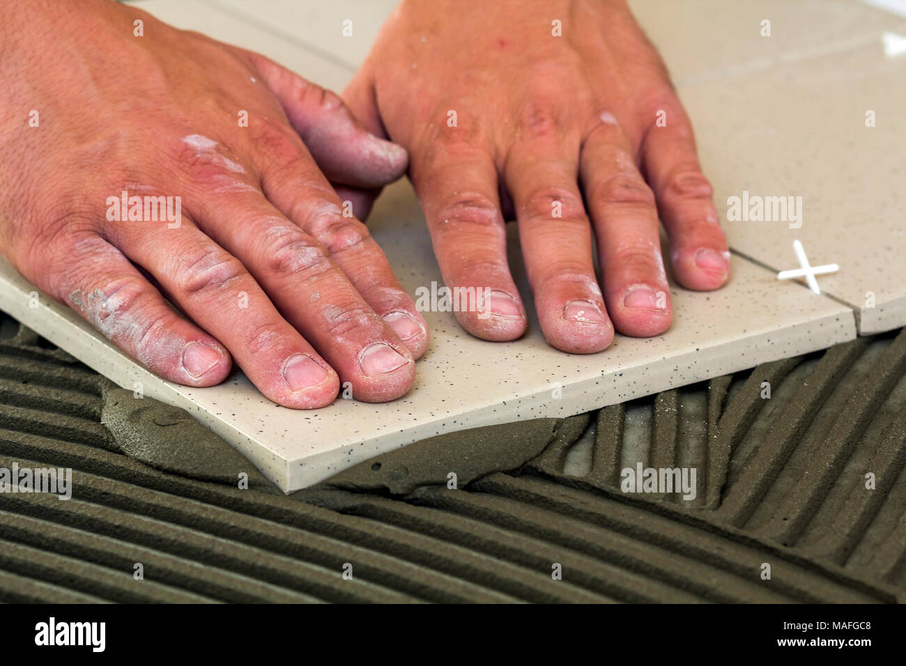 Keramische Fliesen und Werkzeuge für Fliesenleger. Arbeitnehmer hand installieren Bodenfliesen. Home Verbesserung, Renovierung - keramische Fliesen Kleber, Mörtel. Stockfoto