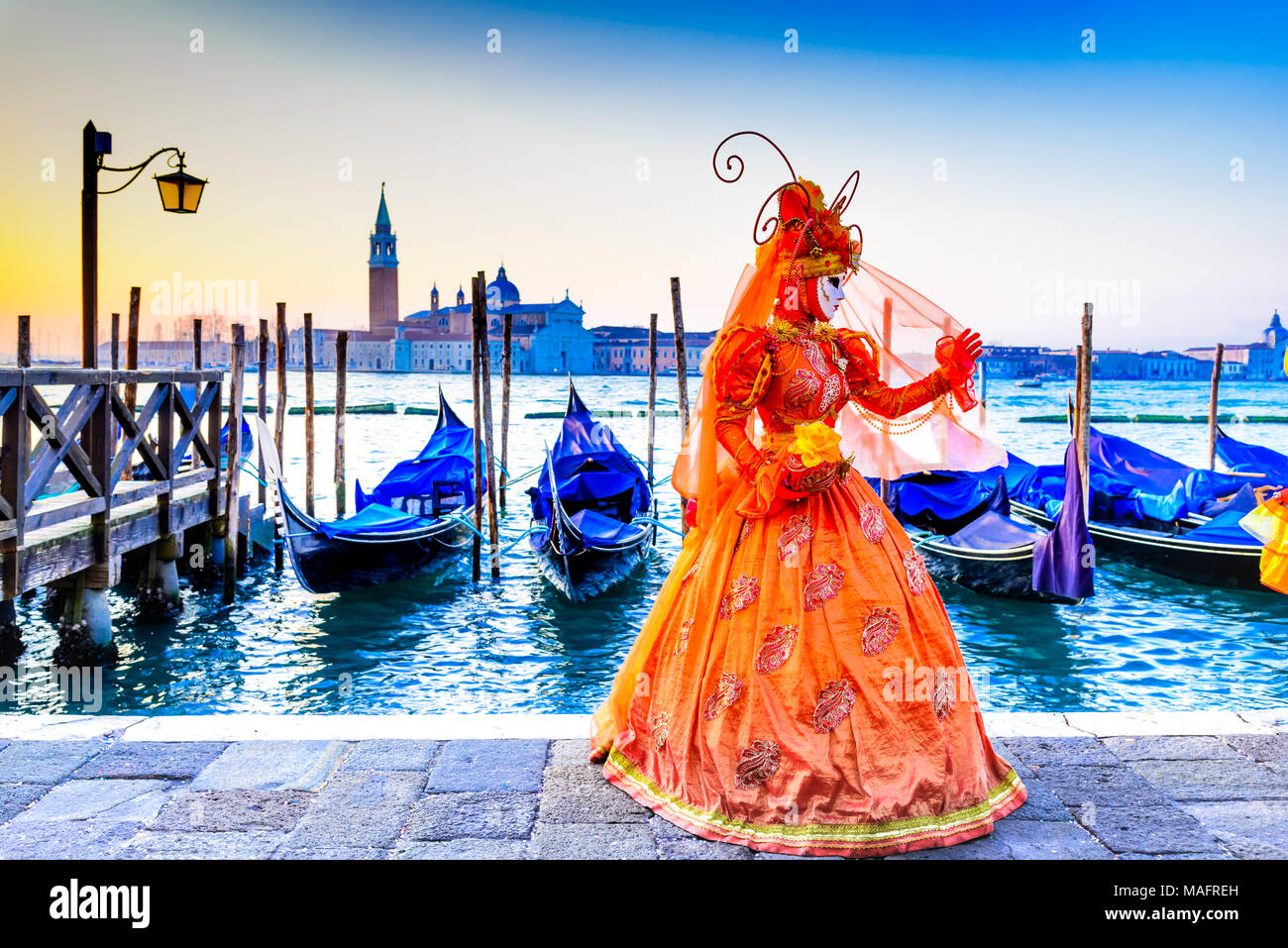 Venedig, Italien - 9. Februar 2018: Karneval in Venedig, wunderschöne Maske an der Piazza San Marco mit Gondeln und Grand Canal. Stockfoto