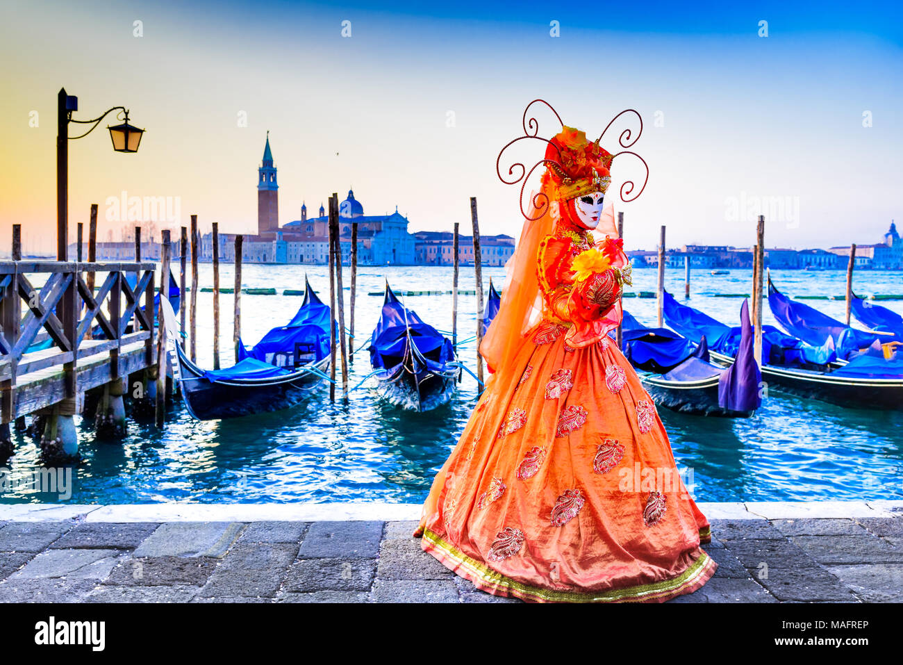 Venedig, Italien - 9. Februar 2018: Karneval in Venedig, wunderschöne Maske an der Piazza San Marco mit Gondeln und Grand Canal. Stockfoto