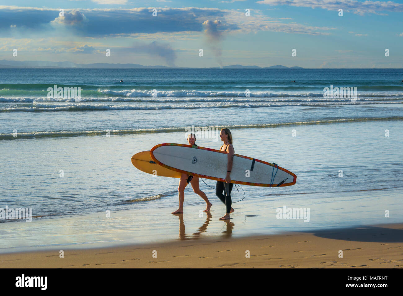 Surfer zu Fuß am Strand entlang am Pass, Byron Bay, New South Wales, Australien Stockfoto