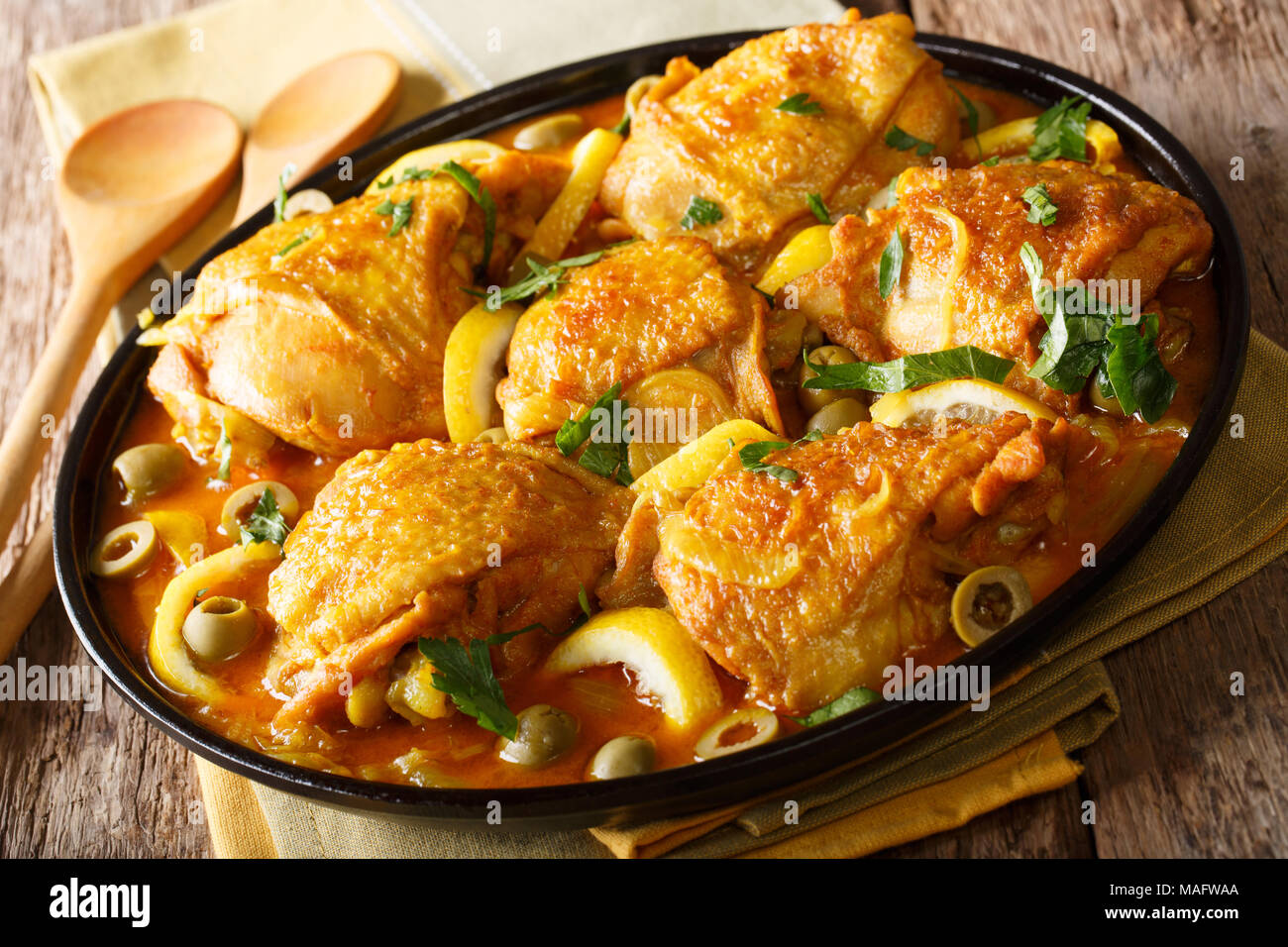 Marokkanische Geschmortes Hähnchen mit Zitronen, Zwiebeln, Gewürze und grüne Oliven close-up auf einem Teller auf dem Tisch. Horizontale Stockfoto