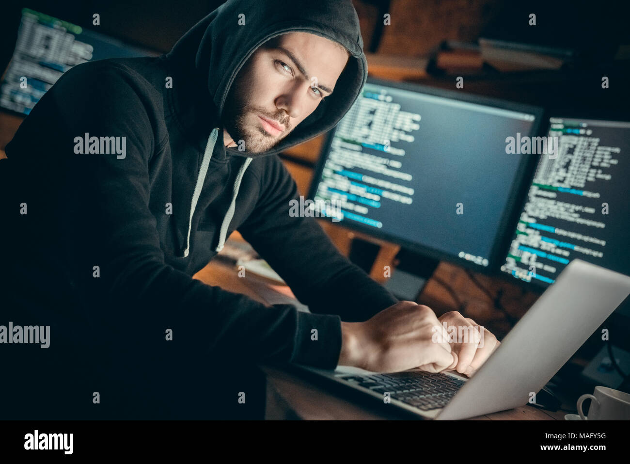 Junger Mann finanzielle Hacker im Büro sitzen am Tisch suchen Kamera vorsichtig Stockfoto