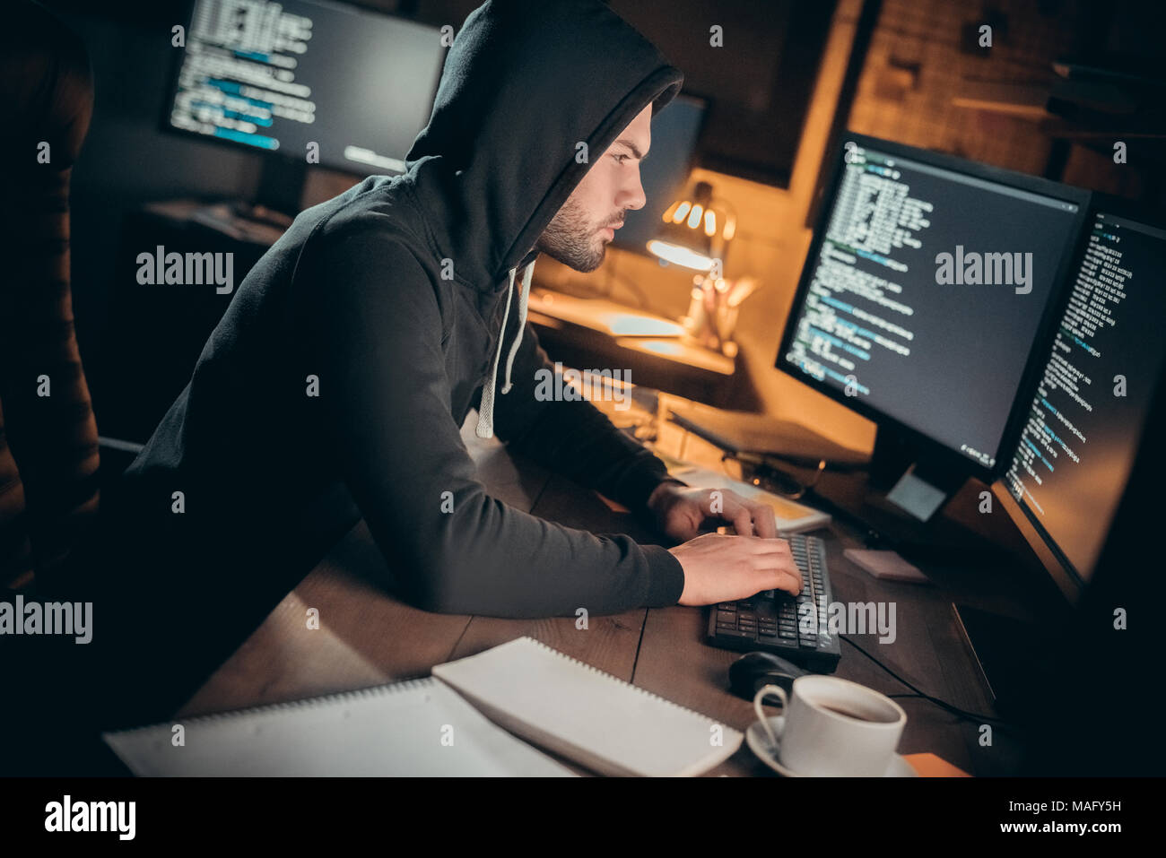 Junger Mann finanzielle Hacker im Büro sitzen am Tisch Eingeben von Code zum Entsperren Daten konzentriert Stockfoto
