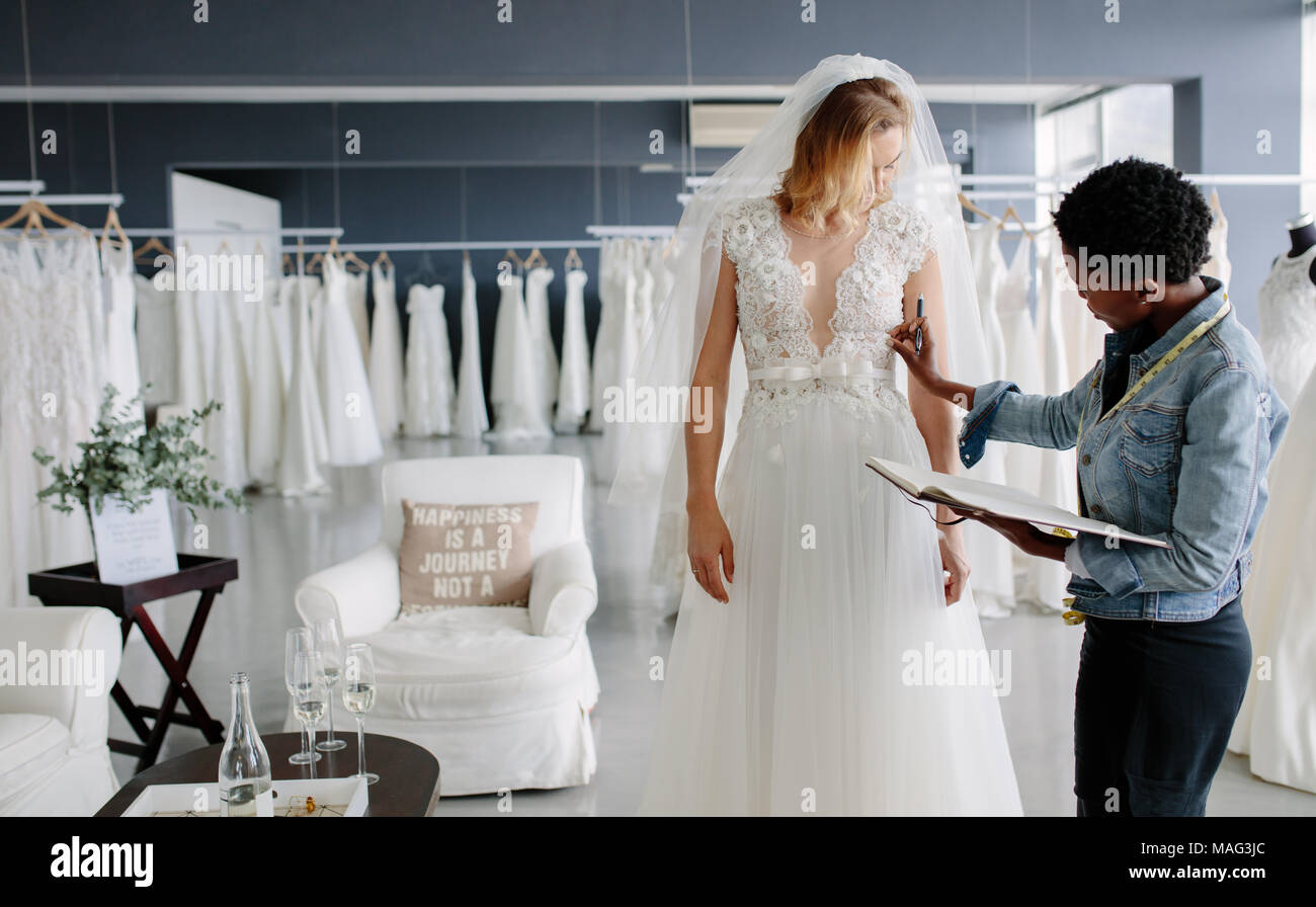 Kleid designer Armatur Brautkleid zu Frau in der Boutique. Frauen und der Einstellung zu Brautkleid in professionelle Fashion Designer Studio. Stockfoto