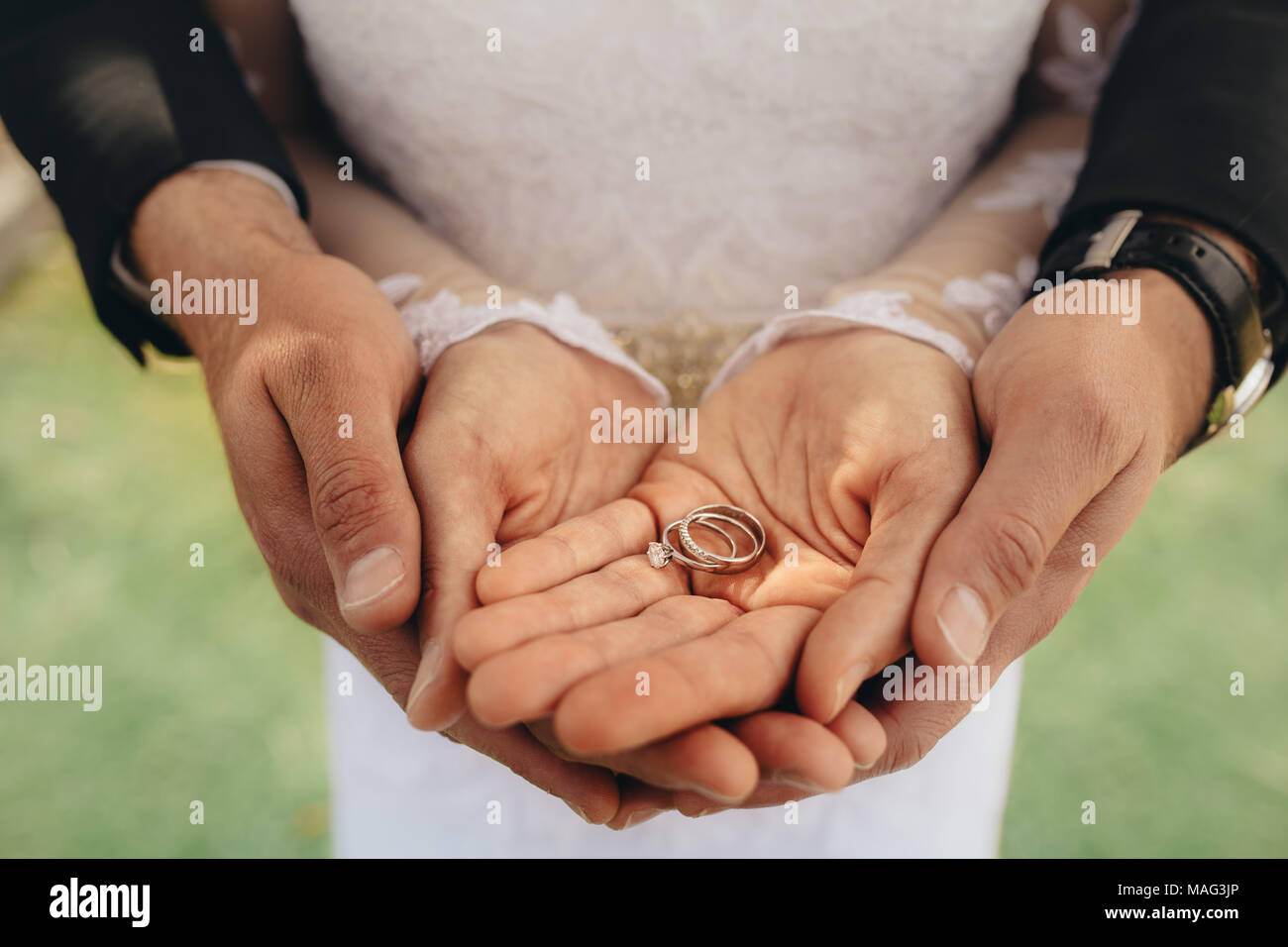 In der Nähe von zwei Trauringe auf Palmen Braut und Bräutigam. Braut und Bräutigam holding Trauringe auf ihre Handflächen während der Zeremonie. Stockfoto