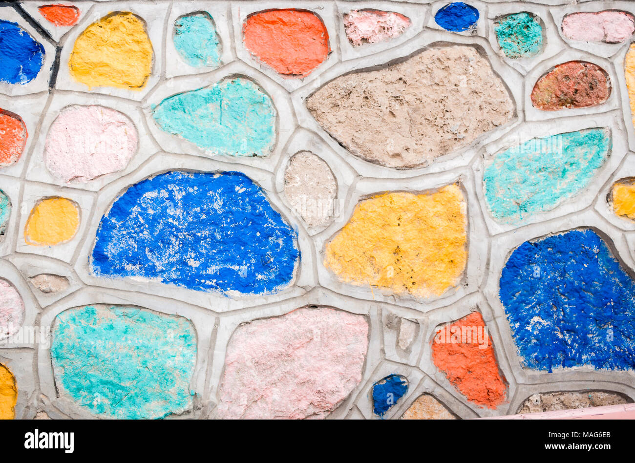 Hintergrund der natürlichen Steine, zusammen mit Zement befestigt und mit bunten Farben bemalt. Stockfoto
