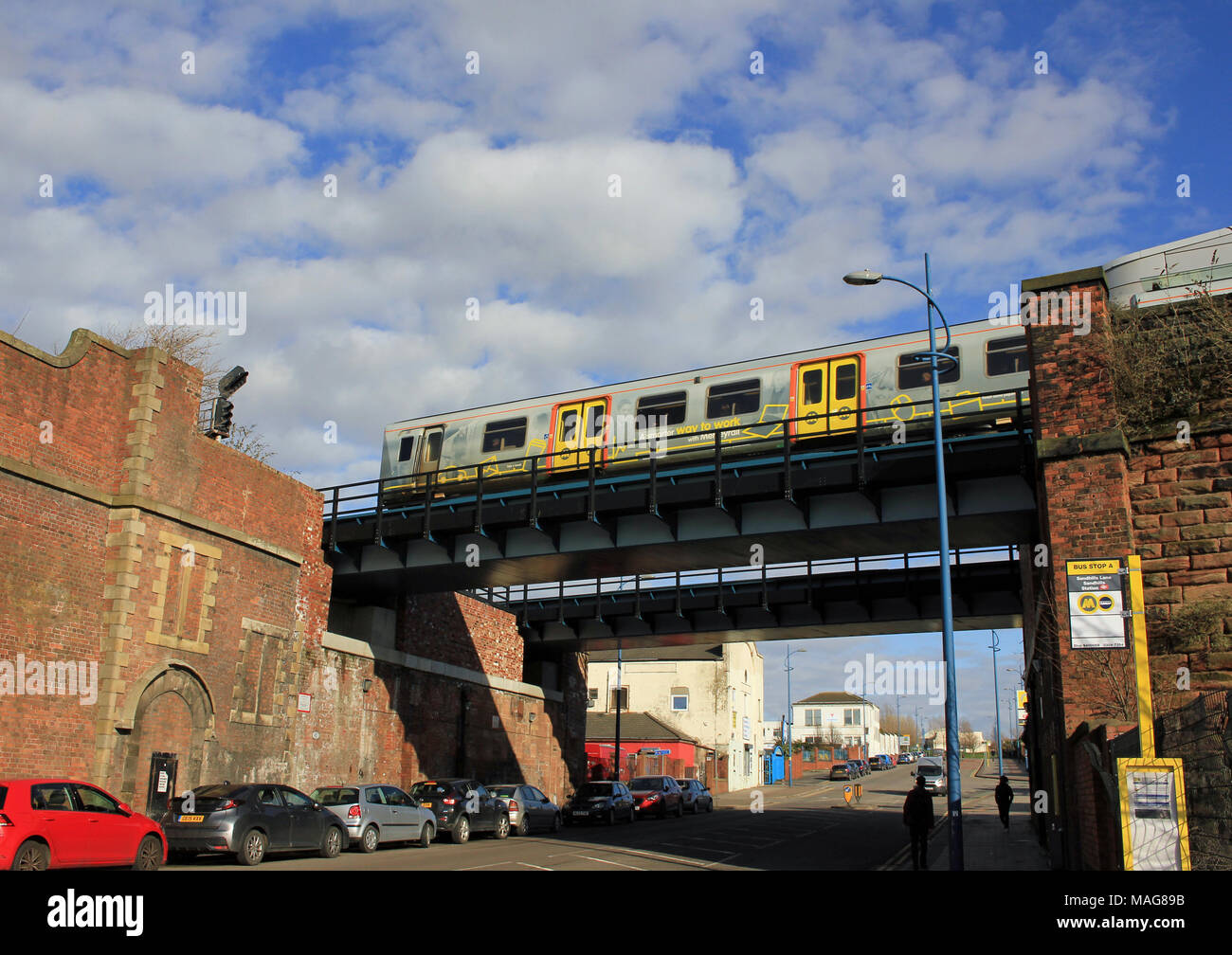 An einem sonnigen Frühlingstag ein mersey Rail elektrische Zug überquert eine Brücke über die Straße, wie es Sandhills station in Liverpool verlässt. Stockfoto
