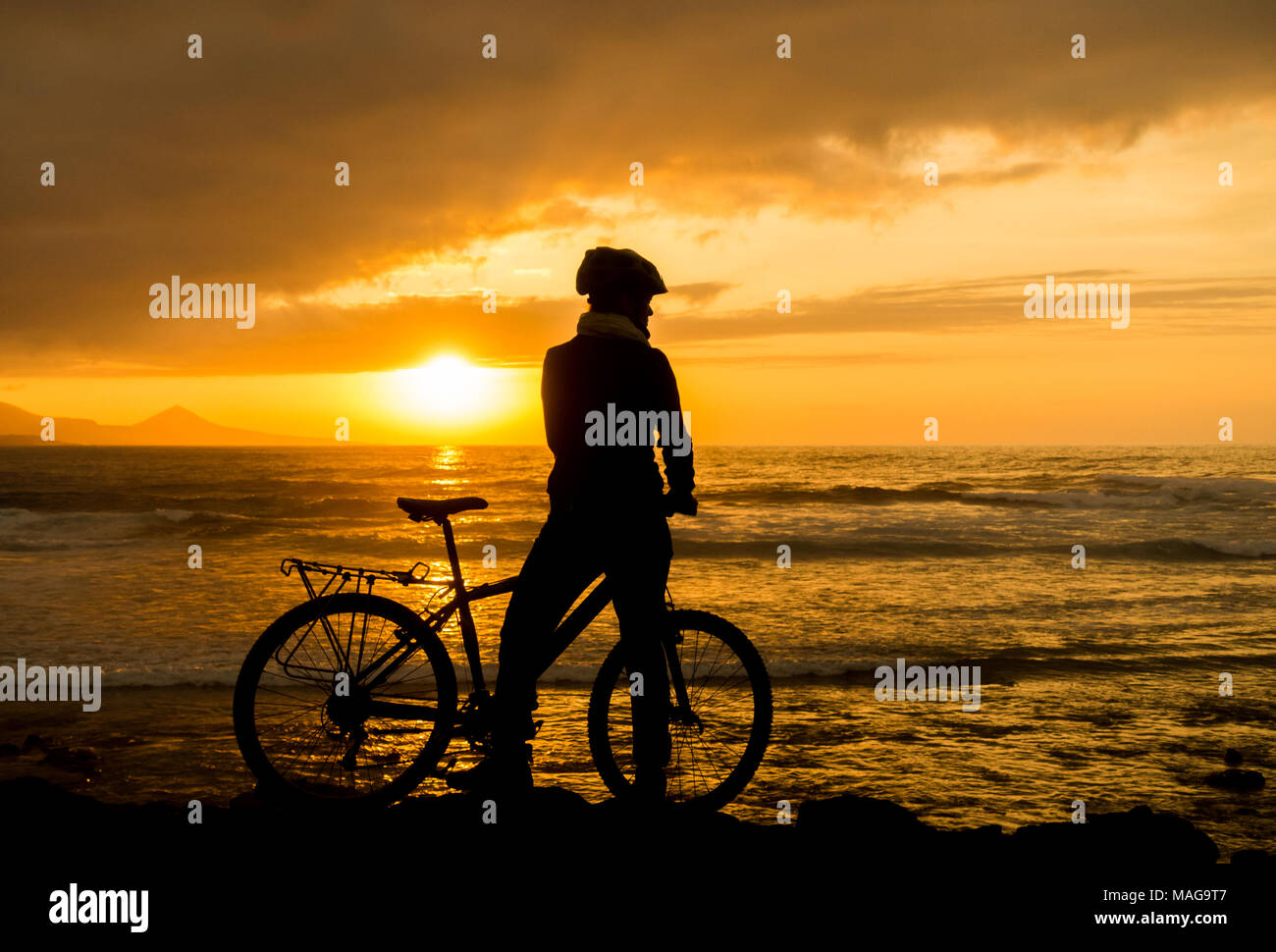 Weibliche Mountainbiker bei Sonnenuntergang an der Nordküste von Gran Canaria, Kanarische Inseln, Spanien Stockfoto