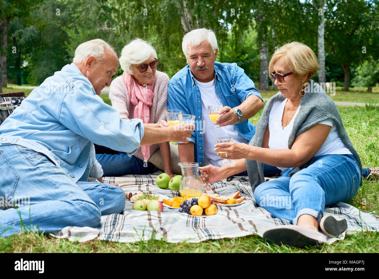 Ältere Leute mit Picknick auf Gras Stockfoto