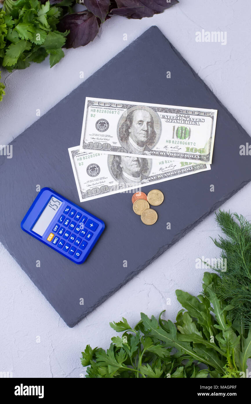 Frische biologische Lebensmittel, Geld und Rechner. Grüne Kräuter Zusammensetzung und Geld. Der Mangel an Geld für gesundes Essen. Stockfoto