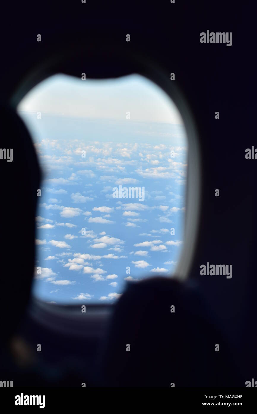 Blick auf den blauen Himmel mit vielen kleinen weißen Wolken aus dunklen Kabine der kommerzielle Fluglinie Flugzeug. Stockfoto