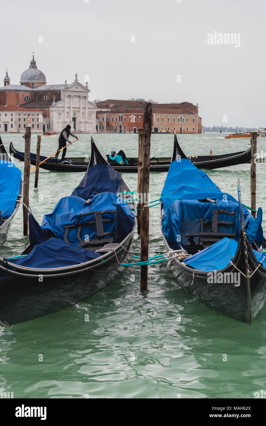 Vertikale Ansicht von angelegten Gondeln und Gondoliere in Venedig im Hintergrund Stockfoto