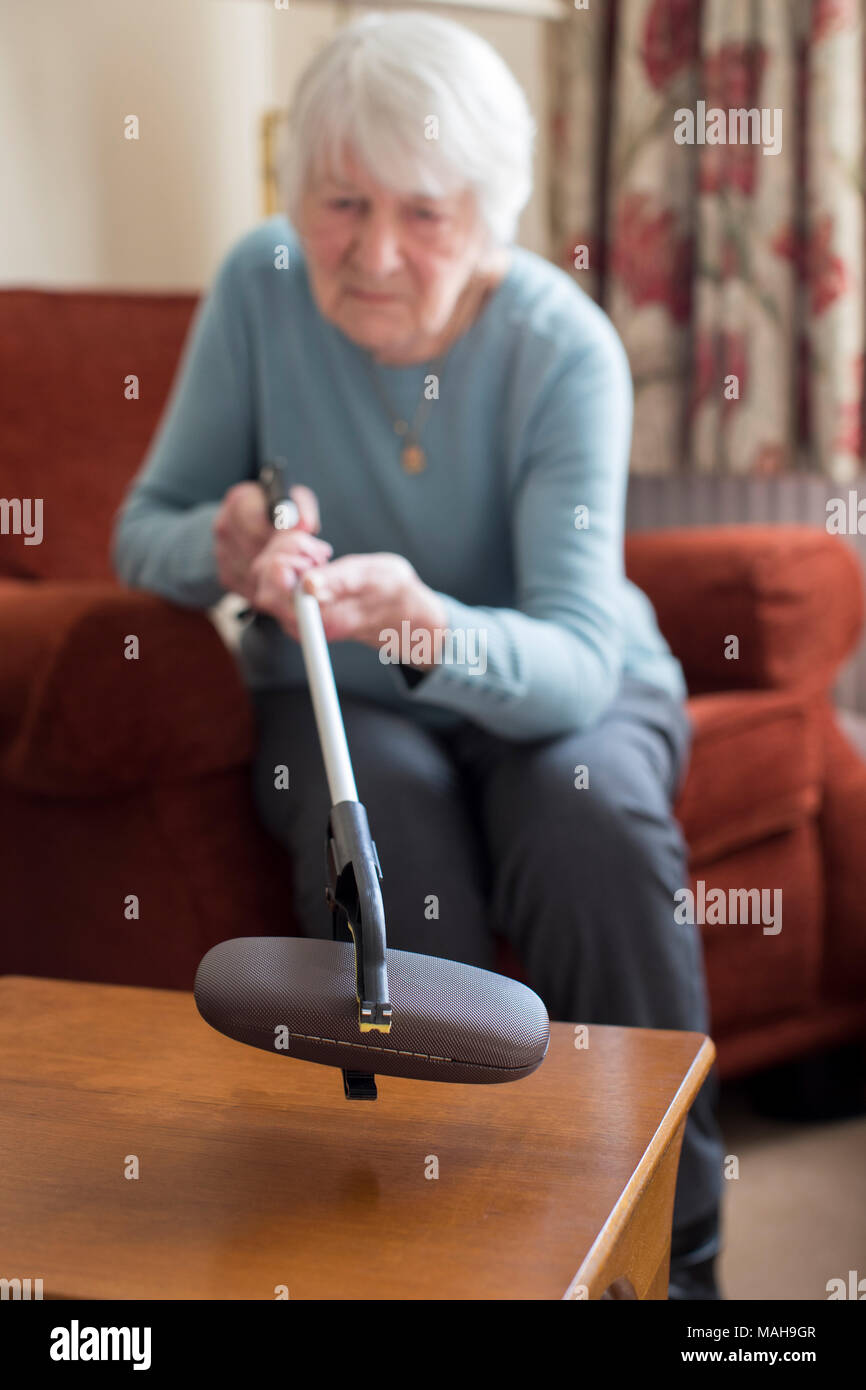 Ältere Frau mit Erreichen Arm Brillenetui zu Hause abholen Stockfoto