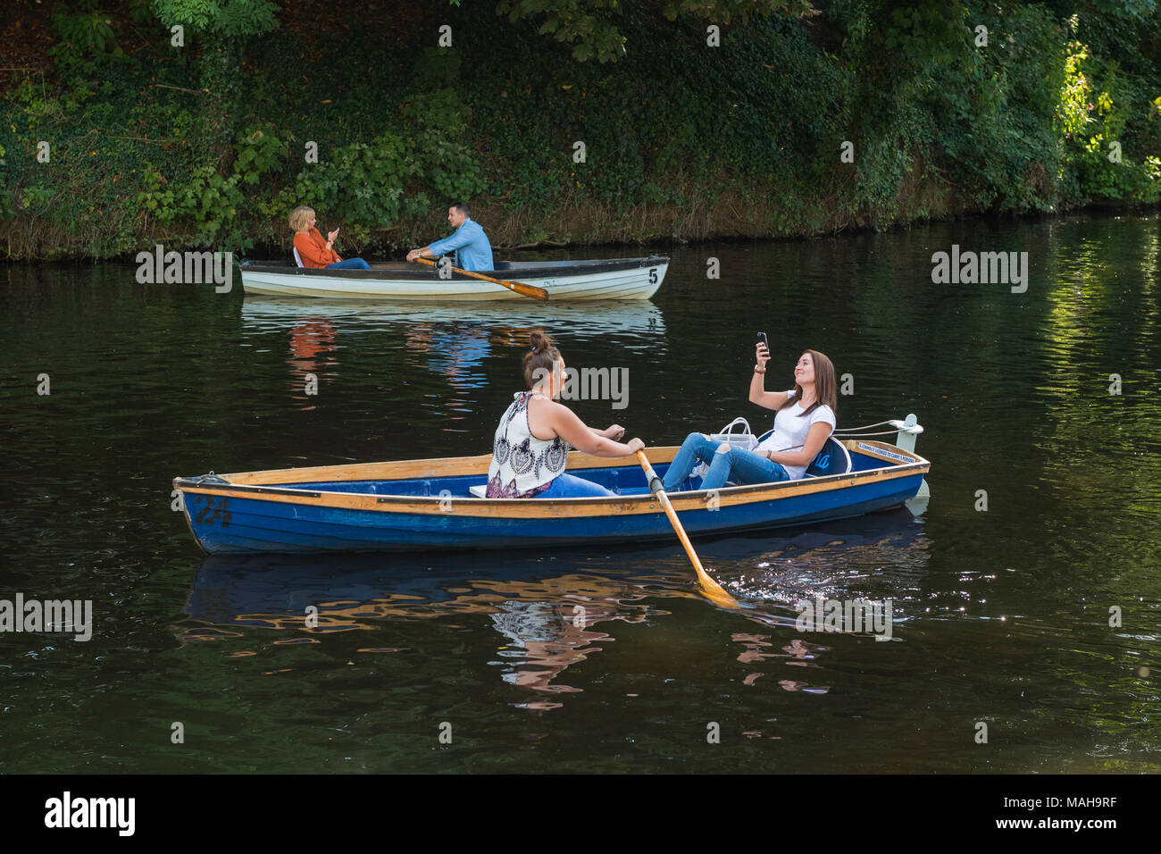 4 Personen fahren, entspannend & Spaß in 2 Ruderboote (1 junge Frau im Boot ist unter selfie) - Flusses Nidd im Sommer, Knaresborough, England, UK. Stockfoto